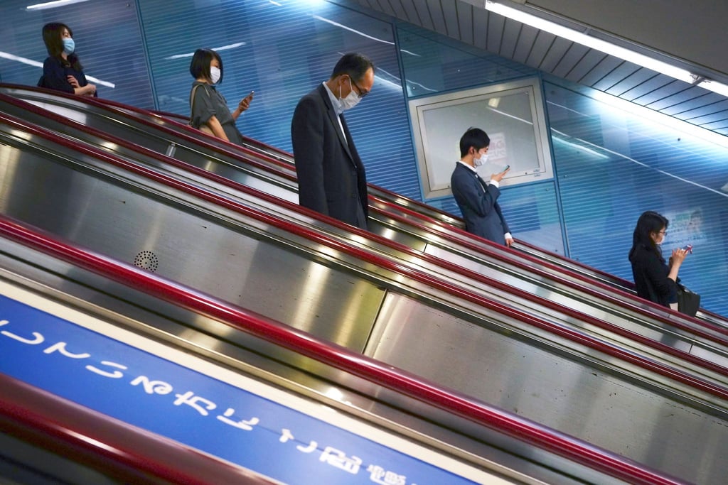 Menschen fahren auf einer Rolltreppe in eine U-Bahn-Station in Tokio.