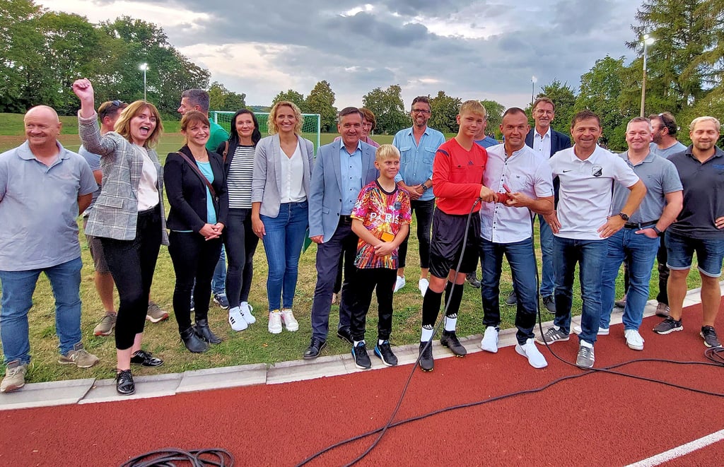 Große Freude am späten Freitagnachmittag in Böhnshausen: Sponsoren, Unterstützer, Helfer, Sportler und Landrat Thomas Balcerowski (Mitte) übergeben die neue Flutlichtanlage des SV Langenstein für den Sportplatz Böhnshausen. Matti Piles (links) und Christian Stoch verbinden dazu zwei Stecker.