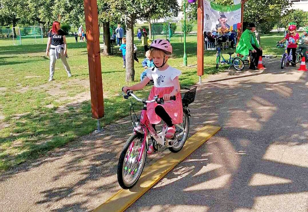 Emmi fährt auf dem Außengelände der Kita über ein Spurbrett im Fahrradparcours der Kreisverkehrswacht.