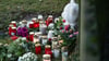 Menschen haben Kerzen, Blumen und ein Stofftier in Gedenken an die tote 14-Jährige vor einen Zaun gelegt.