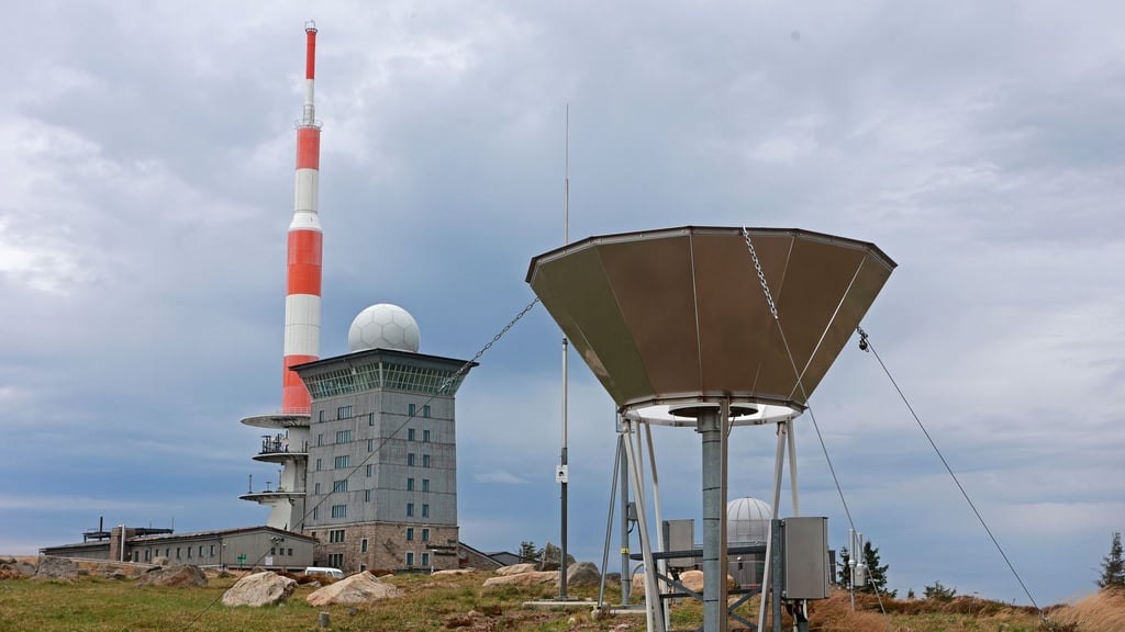 Dunkle Wolken ziehen über den Brocken und die Messinstrumente der Wetterwarte.