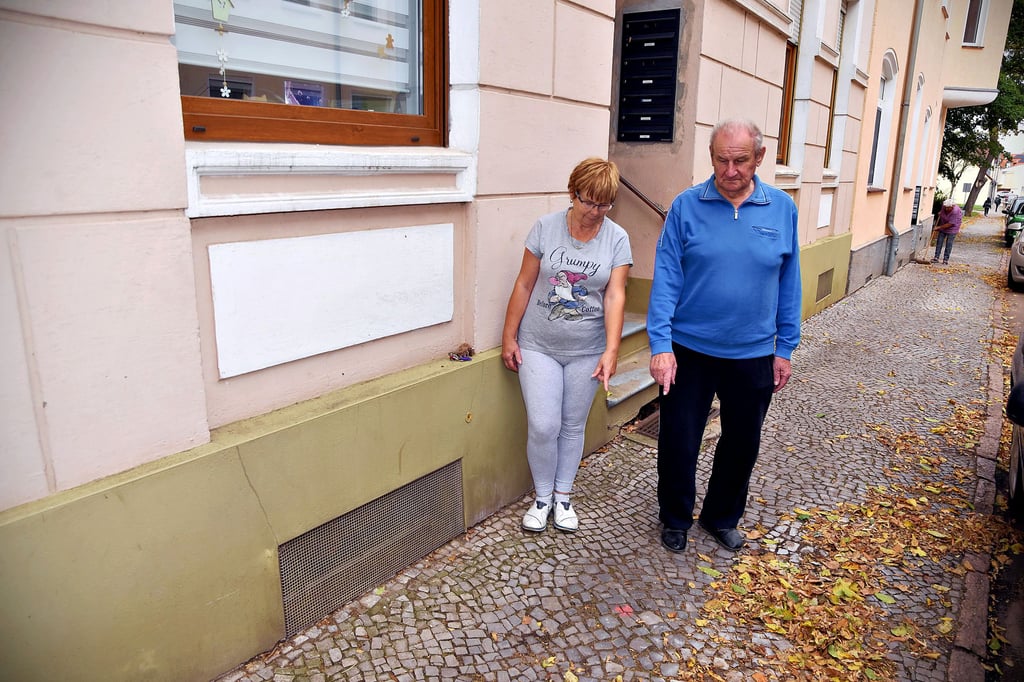 Die Bewohner der Karlstraße 25, Birgit Bartel und Rudolf Herrmanns, zeigen den roten Punkt auf dem Fußweg, wo gebohrt und beschädigt wurde.