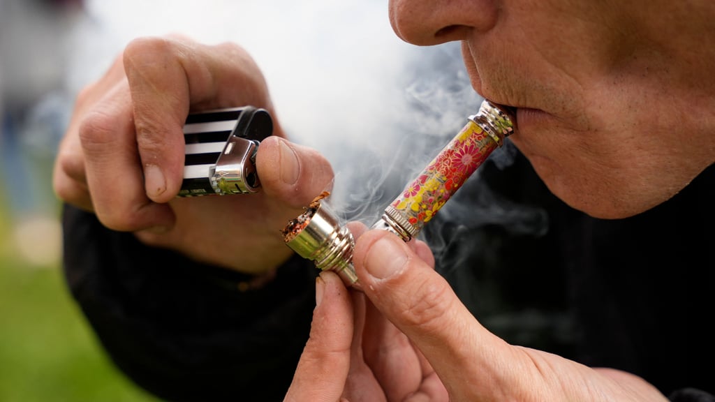 Ein Mann zündet sich eine Cannabis-Pfeife an.