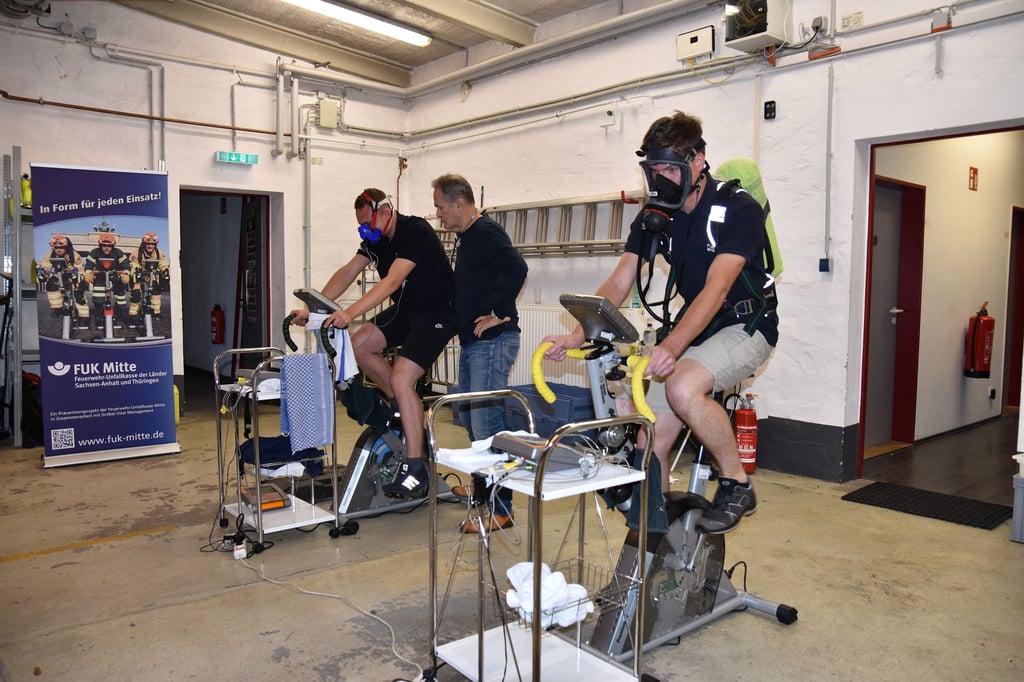 Fabian Dobbert (vorne) und Lucas Feuße sitzen auf dem Ergo-Bike. Minute für Minute wird der Widerstand erhöht. Betreut wird der Test von Helmar Gröbel für die Feuerwehr-Unfallkasse.