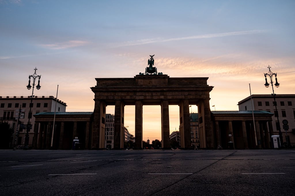 Die Wolken hinter dem Brandenburger Tor sind hell erleuchtet.