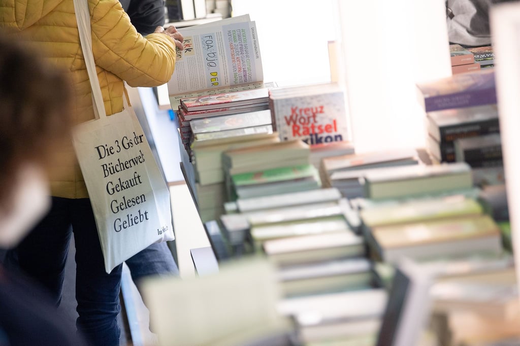 Eine Frau blättert während des ersten Besuchertags der Frankfurter Buchmesse am Stand der Penguin Random House Verlagsgruppe in einem Buch.