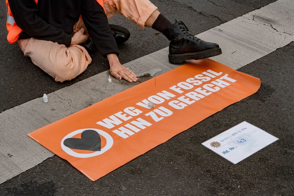 Ein Aktivist der Klimaschutz-Gruppe Letzte Generation sitzt auf einer Straße am Potsdamer Platz.