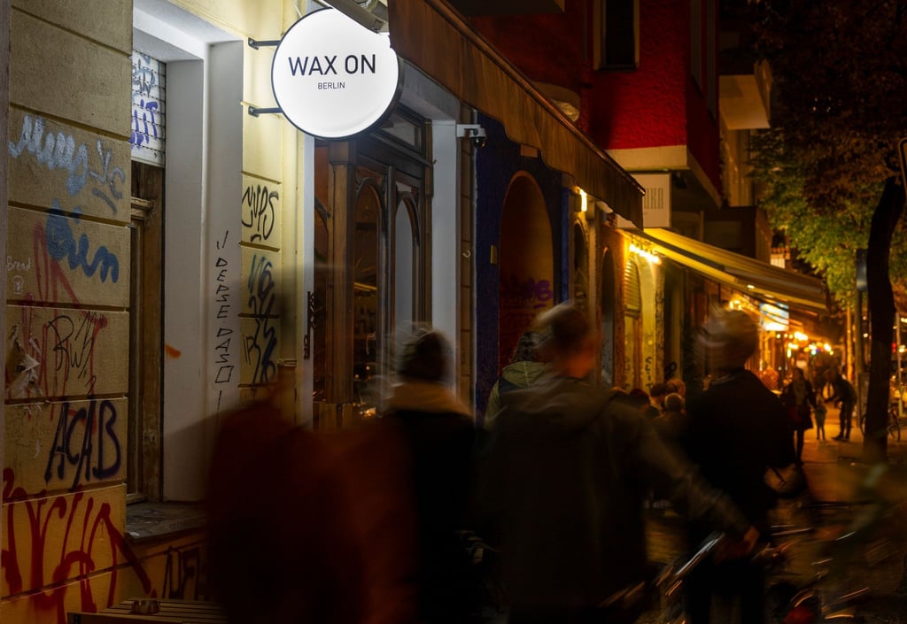 Passanten gehen am Abend vorbei an der Neuköllner Bar "Wax On".