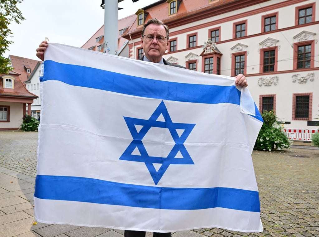 Bodo Ramelow (Die Linke), Ministerpräsident von Thüringen, hält eine israelische Flagge vor der Thüringer Staatskanzlei.