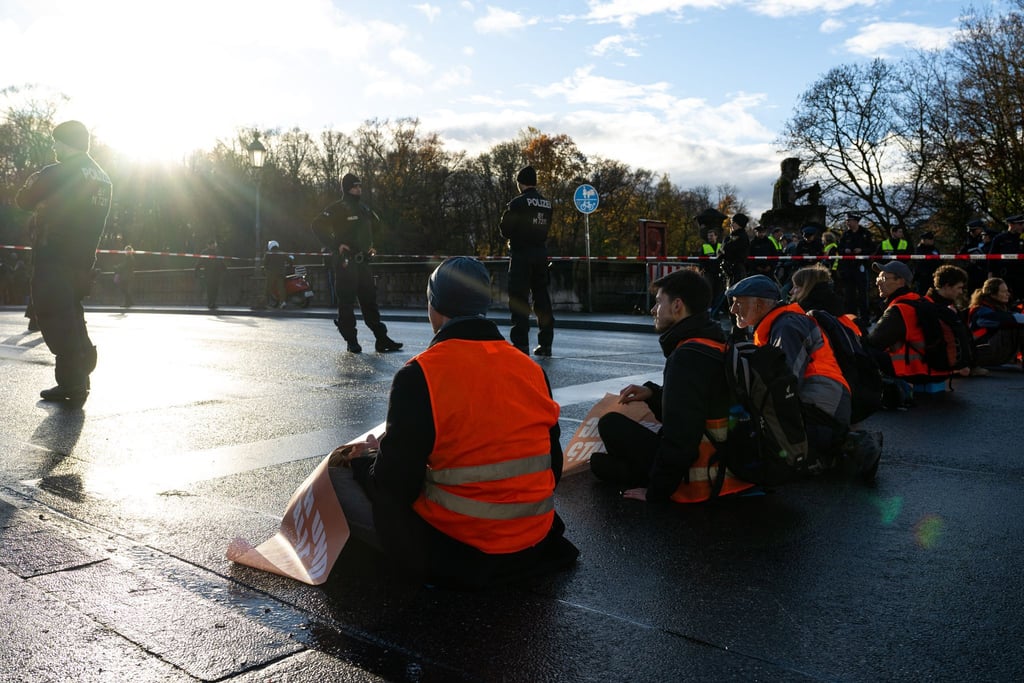 Klimaaktivisten der Umweltschutzbewegung „Letzte Generation“ sitzen auf einer Straße.