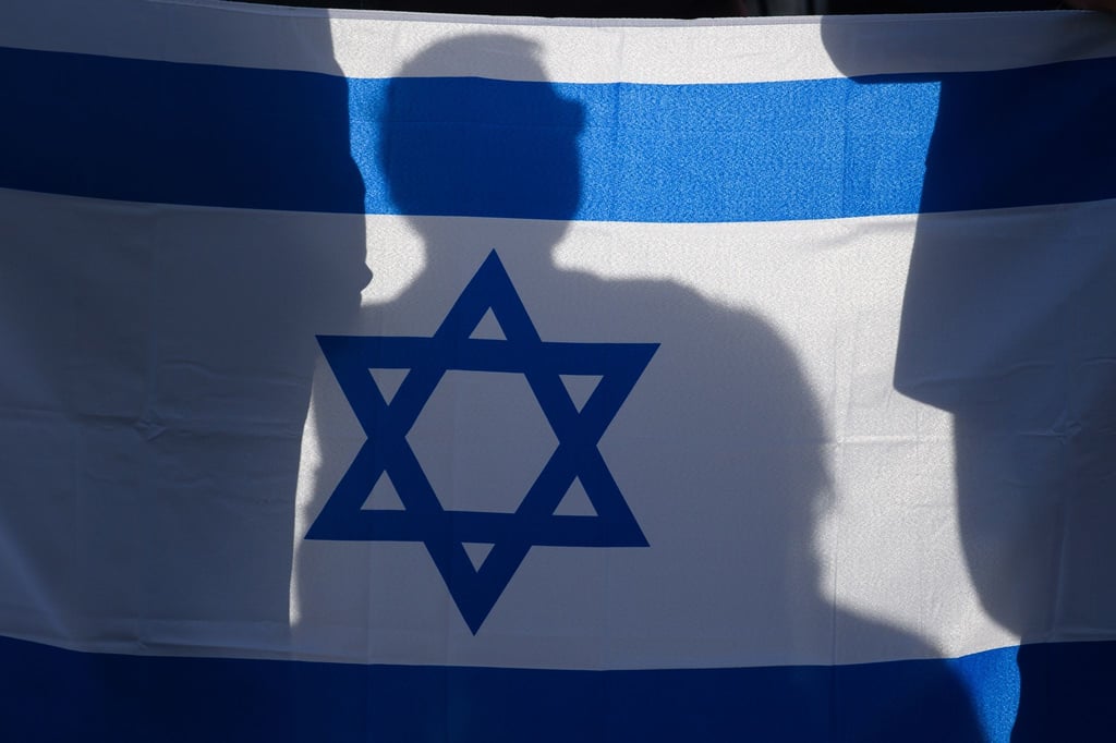 Teilnehmer einer Solidaritätskundgebung für Israel halten die Fahne Israels in den Händen.