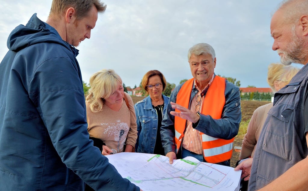 Planer Jörg Reinsberger (mit Warnweste) erklärt die Pläne für das neue Wohngebiet neben dem Agricolagymnsium. Links neben ihm: Sylke Saupe von der Wohnwert Hohenmölsen GmbH, dem Investor des Bauprojekts.
