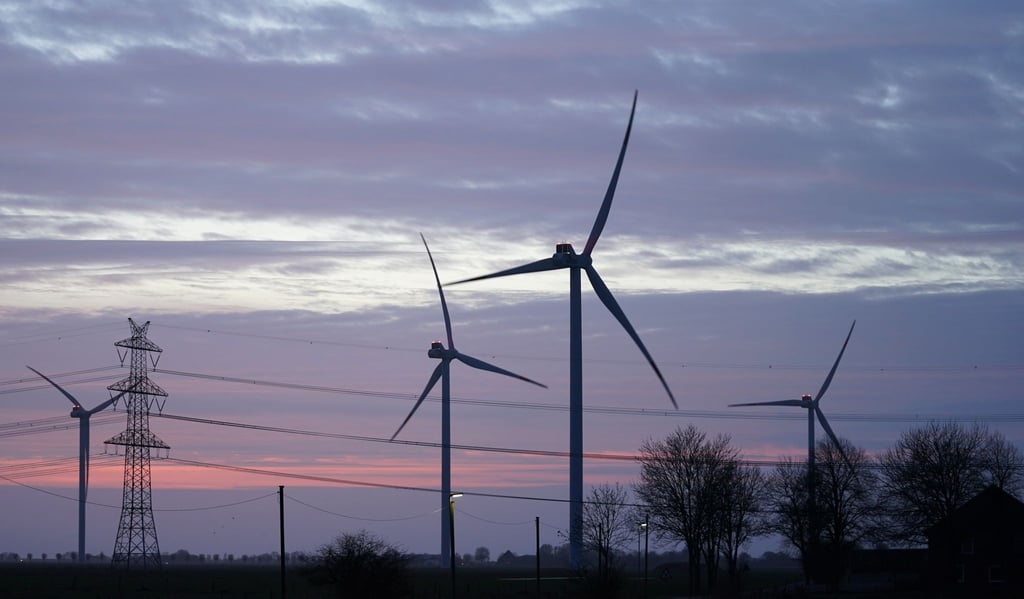 Windräder und Stromleitungen sind im Abendlicht zu sehen.