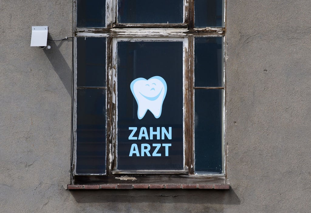 Zahnarzt steht an einem Fenster eines Hauses geschrieben, in dem sich eine Zahnarztpraxis befindet.