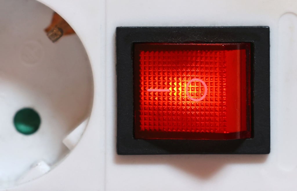 Der eingeschaltete Schutzschalter einer Mehrfachsteckdose leuchtet rot.