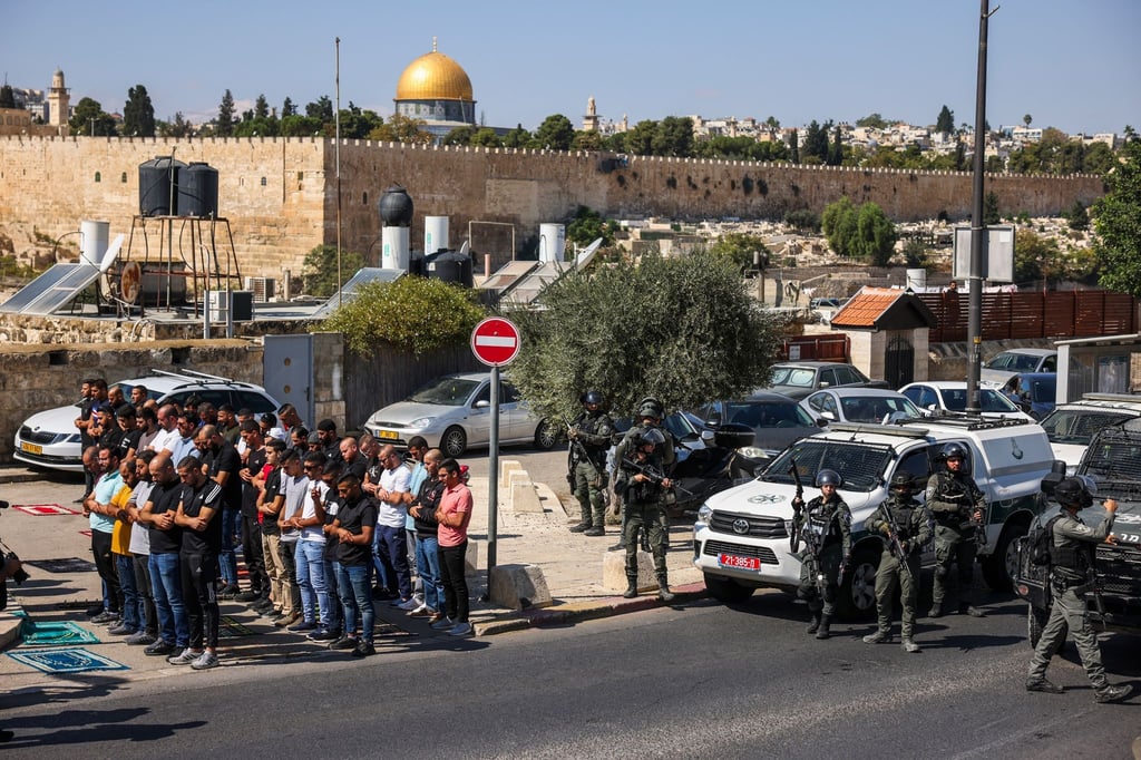 Palästinensische Gläubige beten außerhalb der Altstadt von Jerusalem, während israelische Streitkräfte Wache stehen.