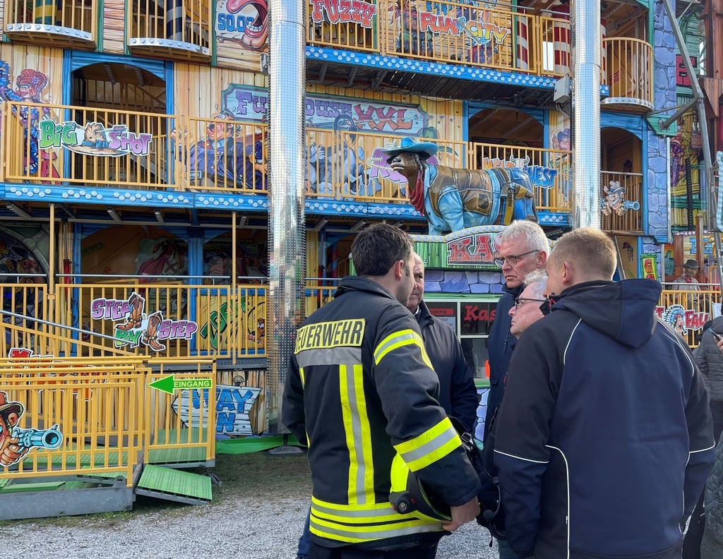 Feuerwehrleute und Polizisten stehen vor dem Funhouse auf dem Pollhansmarkt in Schloß Holte-Stukenbrock.