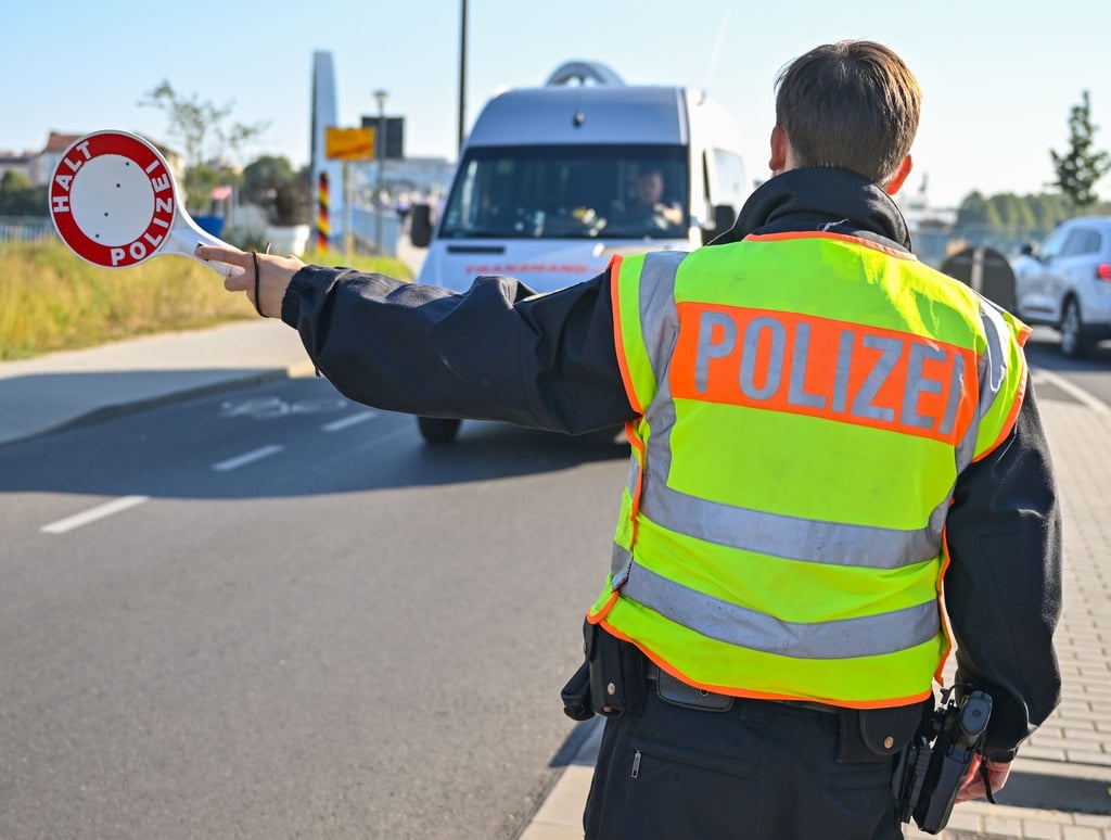 Ein Beamter der Bundespolizei stoppt den Fahrer eines Kleintransporters.