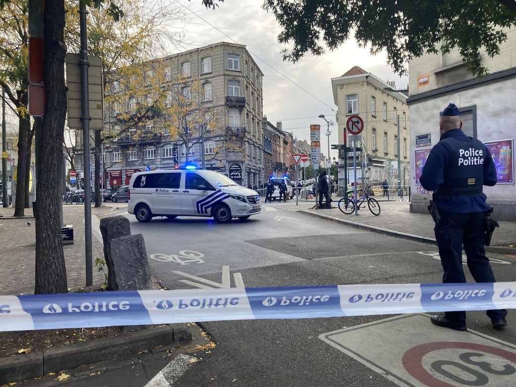 Die Polizei sperrt eine Straße, während ein Polizist hinter Absperrband Wache steht.