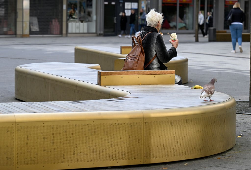 Eine Frau sitzt auf einer der goldenen Bänke in Wuppertal.