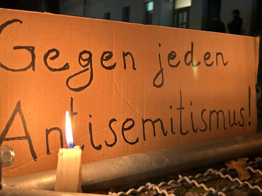 Eine brennende Kerze steht vor einem Schild mit der Aufschrift "Gegen jeden Antisemitismus“ bei einer Mahnwache gegen Antisemitismus nach dem versuchten Brandanschlag in der Nacht zum Mittwoch auf die Synagoge in der Berliner Brunnenstraße.