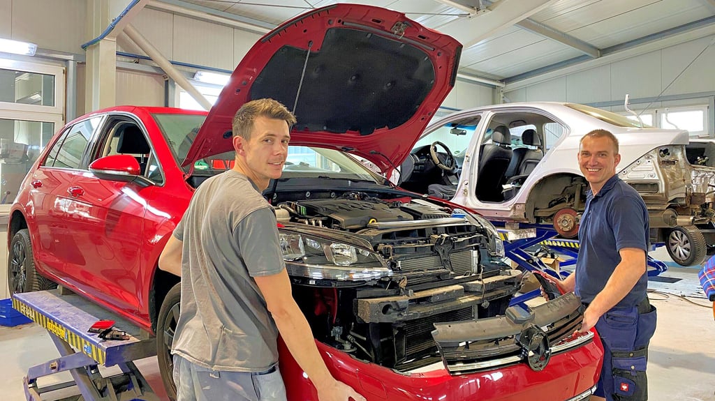 Die Mitarbeiter Michael Schink (33, links im Bild) und Jens Sokolow (42) arbeiten an der Karosserie eines Autos.