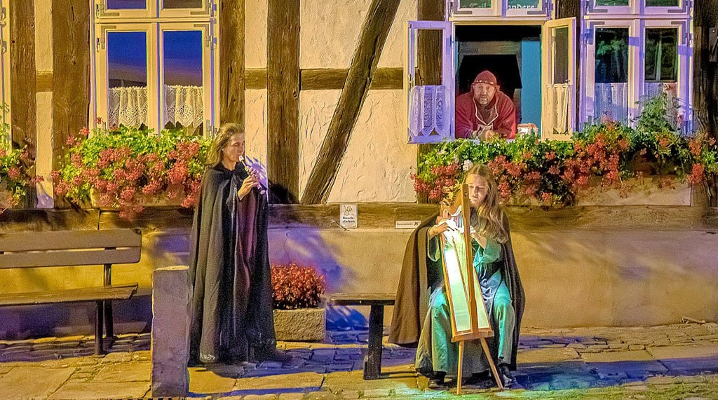 Aus dem Fenster schaut Minnesänger Oliver Wolf. Auf der Flöte  spielt Gemahlin Michaela und  auf der Harfe Tochter Liona. Das Trio zählt zum Chor All Cantara.
