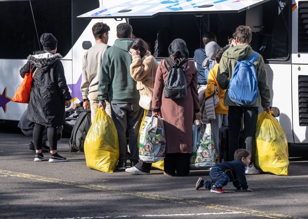 Flüchtlinge gehen in der einer Erstaufnahmeeinrichtung zu einem wartenden Bus.