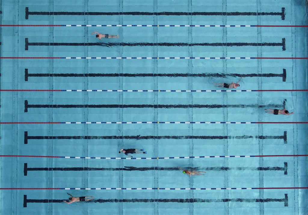 Menschen schwimmen in einem Freibad.