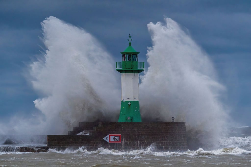 Wellen der Ostsee peitschen bei einem schweren Sturmtief an den Leuchtturm auf der Ostmole. Wegen des Sturmtiefs sind an der Ostseeküste Straßen und Uferbereiche vom Hochwasser überschwemmt worden.