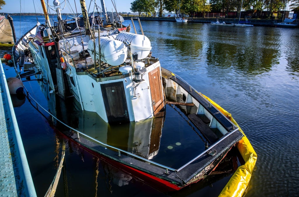 Ein Fischkutter liegt nach der Sturmflut teilweise gesunken vor dem Sperrwerk von Wieck.