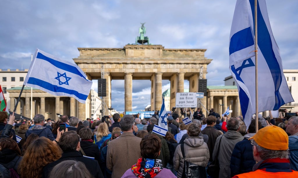 Teilnehmer der Kundgebung „Aufstehen gegen Terror, Hass und Antisemitismus – in Solidarität und Mitgefühl mit Israel“ vor dem Brandenburger Tor schwenken israelische Flaggen.