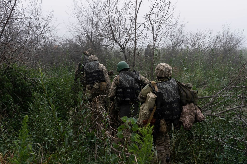 Ukrainische Marinesoldaten gehen durch Gelände an der Frontlinie in Cherson.