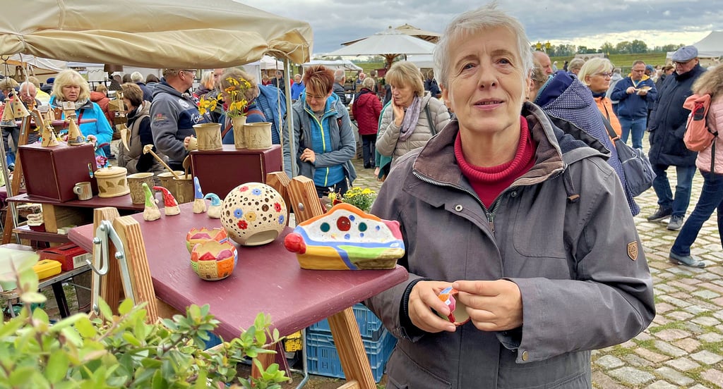 Angelika Otto hat den Töpfermarkt nach Tangermünde geholt – und auch die Bank (kleines Modell neben ihr), Vor ihrer ehemaligen Wirkungsstätte am Neustädter Tor wurde die Bank von ihr entworfen und gemeinsam mit heimischen Handwerkern realisiert.