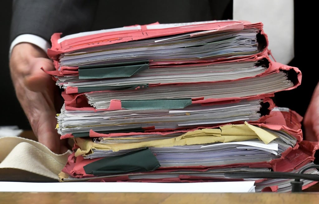 Prozessakten werden zu Beginn einer Verhandlung in einem Gerichtssaal auf einen Tisch gelegt.