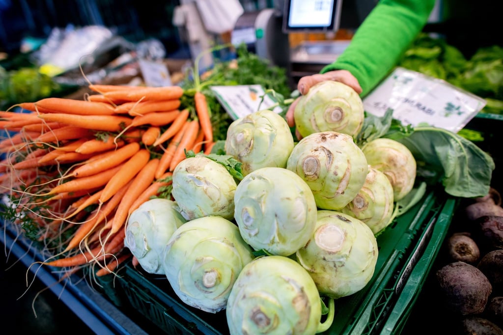 Kohlrabi und Karotten stehen an einem Obst- und Gemüsestand.
