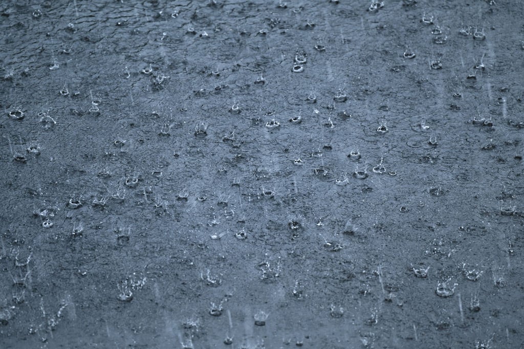 Starkregen prasselt während eines Gewitters auf eine Straße.