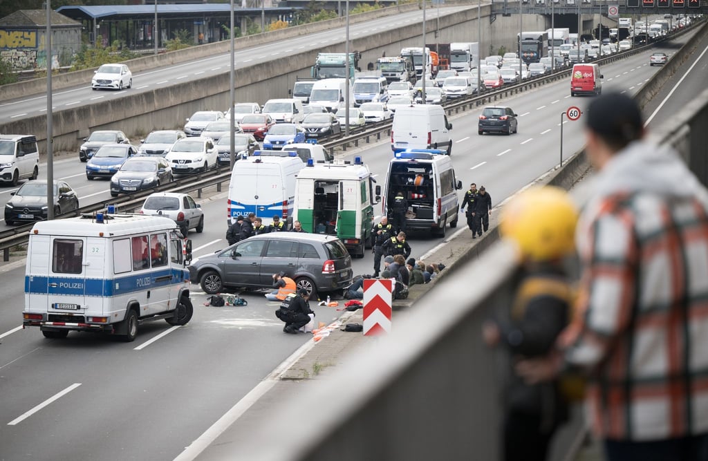 Ein Aktivist klebt während einer Straßenblockade der Klimaschutzgruppe "Letzte Generation" unter einem Auto.