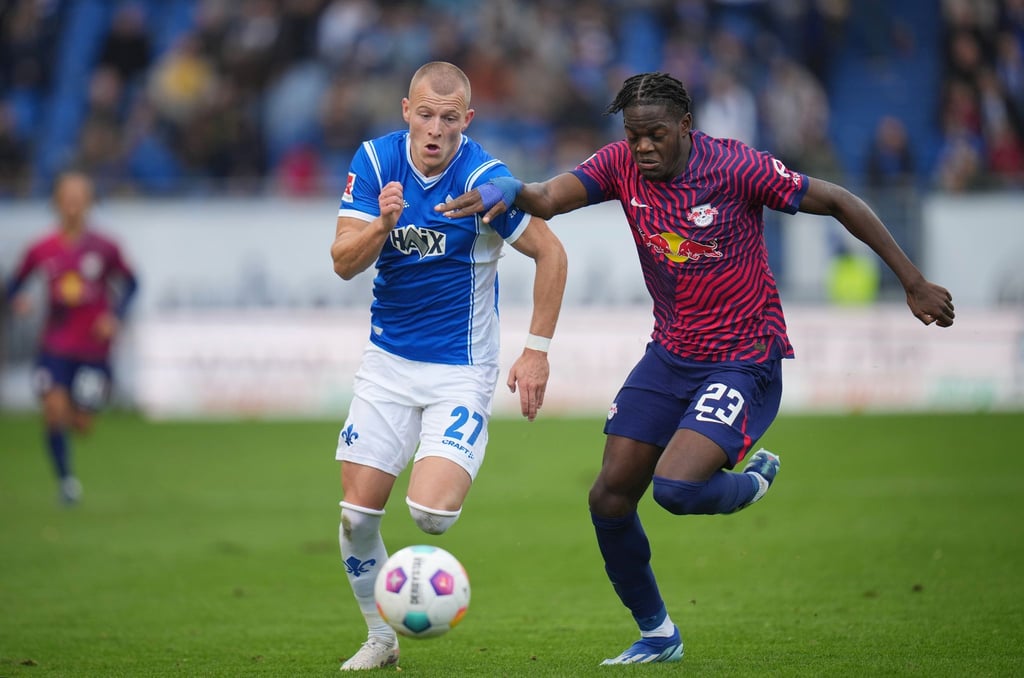 Leipzigs Castello Lukeba(r) und Darmstadts Tim Starke kämpfen um den Ball.