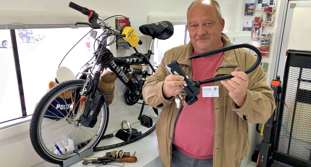 Fred Brehmeier vom Landeskriminalamt zeigt im Präventionsmobil ein Fahrradschloss, das was taugt - anders als „abschließbare Geschenkbänder“.