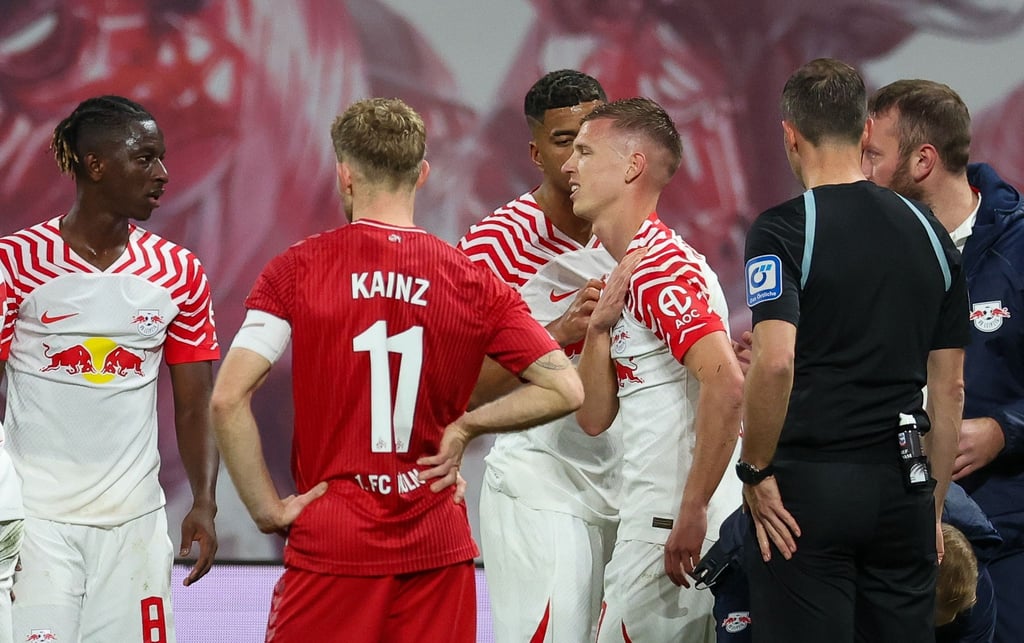 Dani Olmo (3.v.l) vom RB Leipzig geht mit schmerzverzerrtem Gesicht vom Feld.