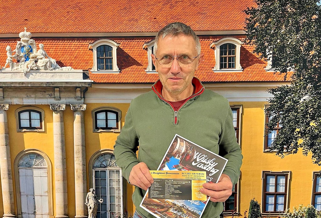 Michael Frühauf vor der Fototapete, mit dem Motiv des Schlosses Mosigkau, in der Vollwertkochschule, die von seiner Frau betrieben wird.