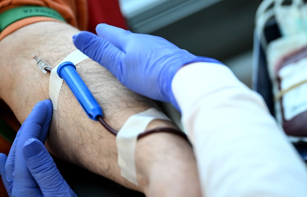Eine Nadel mit Schlauch steckt in einem Arm eines Mannes bei einer Blutspendeaktion des DRK.