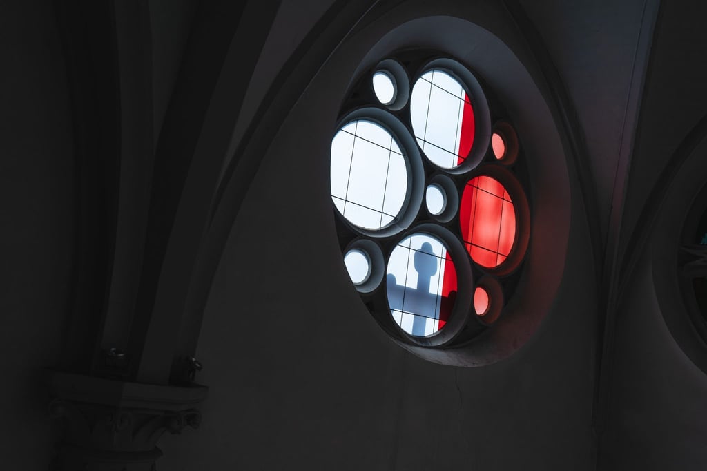 Licht wirft den Schatten eines Kreuzes durch ein Kirchenfenster.