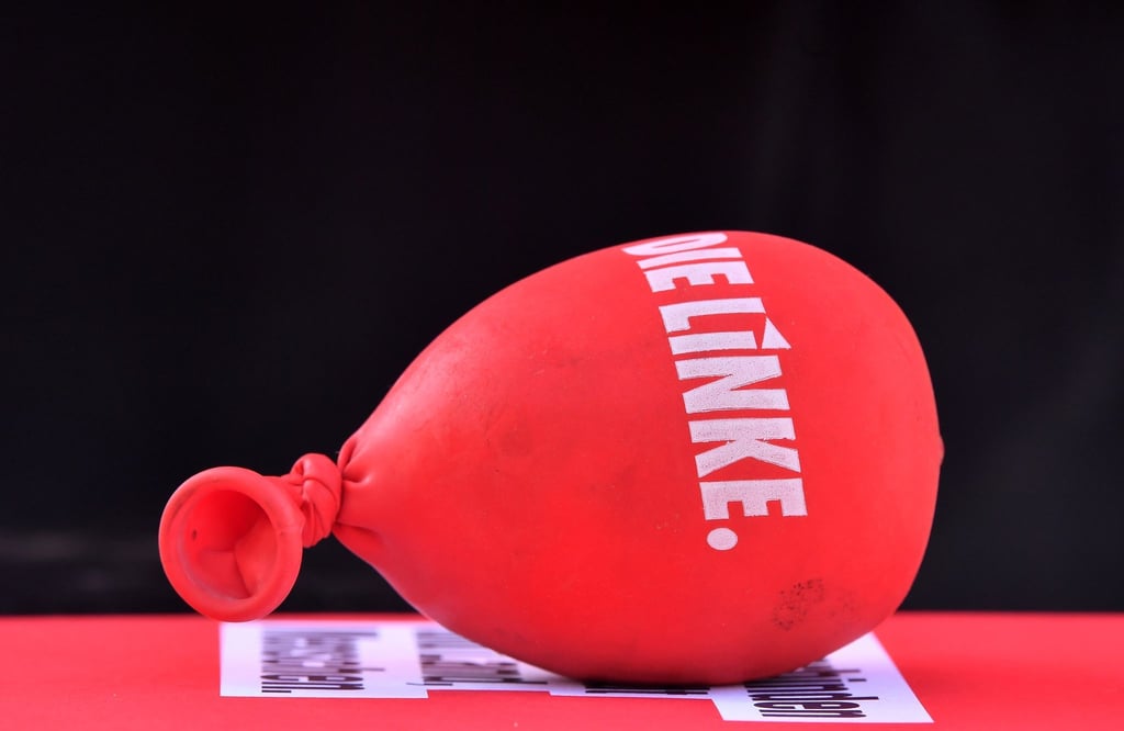 Ein mit Sand gefüllter Luftballon mit dem Aufdruck "Die Linke" liegt auf einem Tisch.
