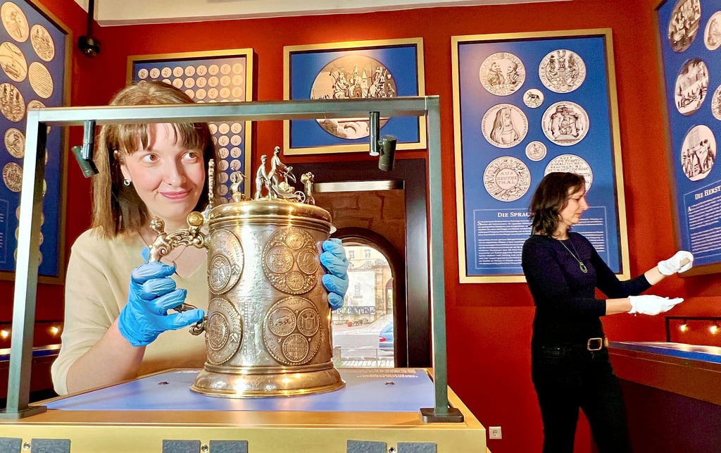 Christiane Heinevetter (links) stellt die „Lehmersche Bergkanne“ in die Vitrine. Jacqueline Fox räumt indes die Münzen in die Vitrine.