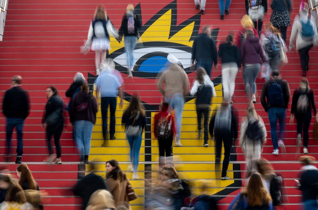 Besucherinnen und Besucher gehen zu Beginn des Messetages über eine Treppe mit dem Logo der Leipziger Buchmesse..
