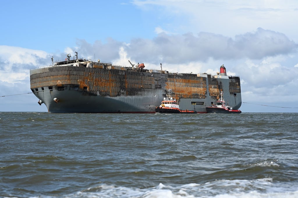 Schlepper begleiten den schwer beschädigten Autofrachter “Fremantle Highway„ in den Hafen.