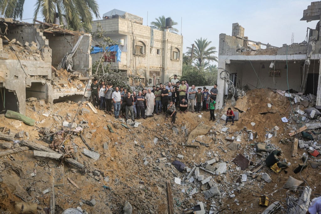 Palästinenser stehen in Chan Junis im Gazastreifen um einen Krater herum, der durch einen israelischen Angriff verursacht wurde.