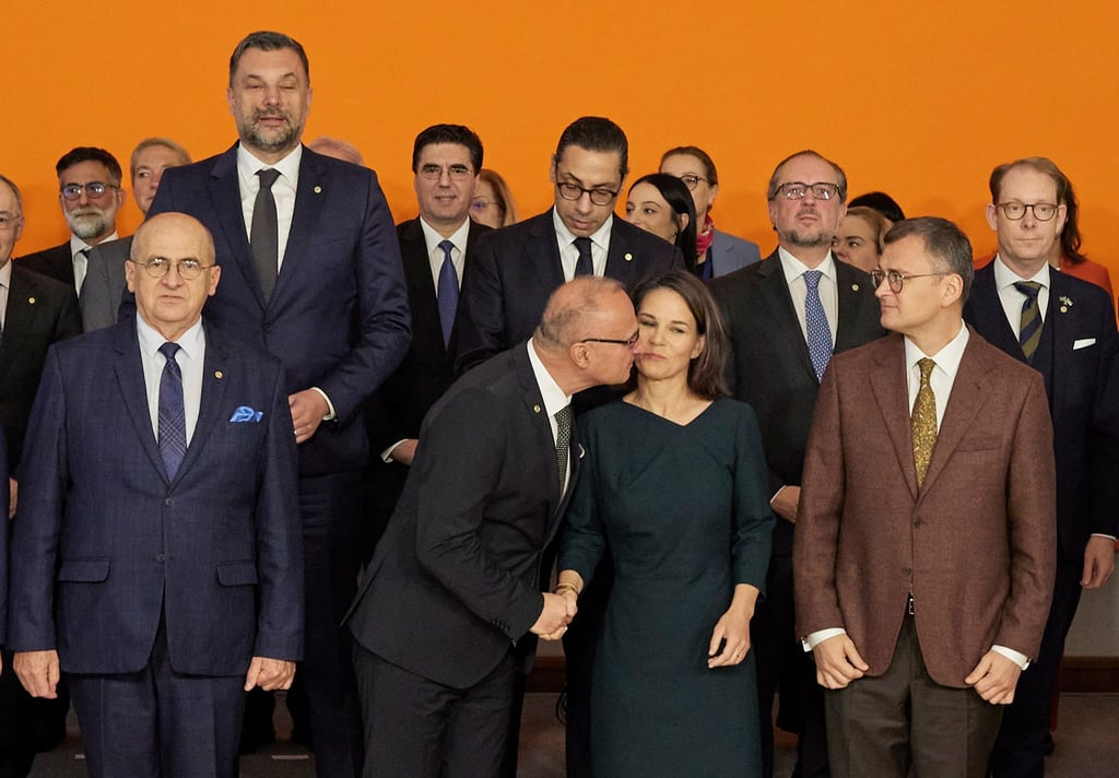 Der kroatische Außenminister Gordan Grlić Radman begrüßt Annalena Baerbock mit einen Kuss beim Gruppenbild im Rahmen der Europakonferenz in Berlin.